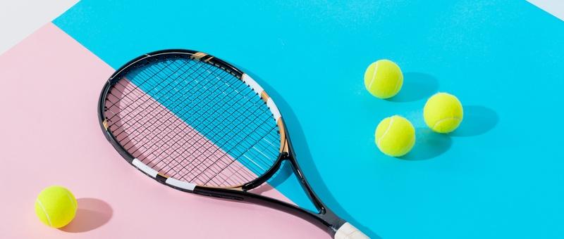 Tennis racket and yellow tennis balls against pink and blue background.