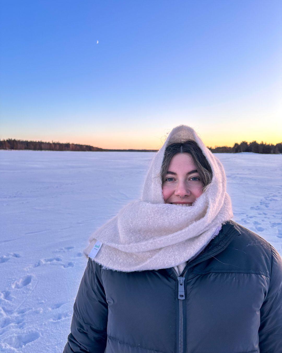Young woman wearing winter clothing against a snowy backdrop.