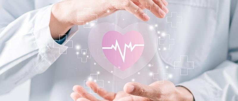 Healthcare professional's hands surrounding a digital pink heart with heartbeat line, surrounded by medical cross symbols.