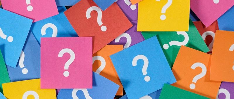 White question marks printed on assorted brightly-coloured post-it notes.