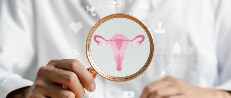 Hand holding magnifying glass showing pink uterus diagram with medical icons floating in background.