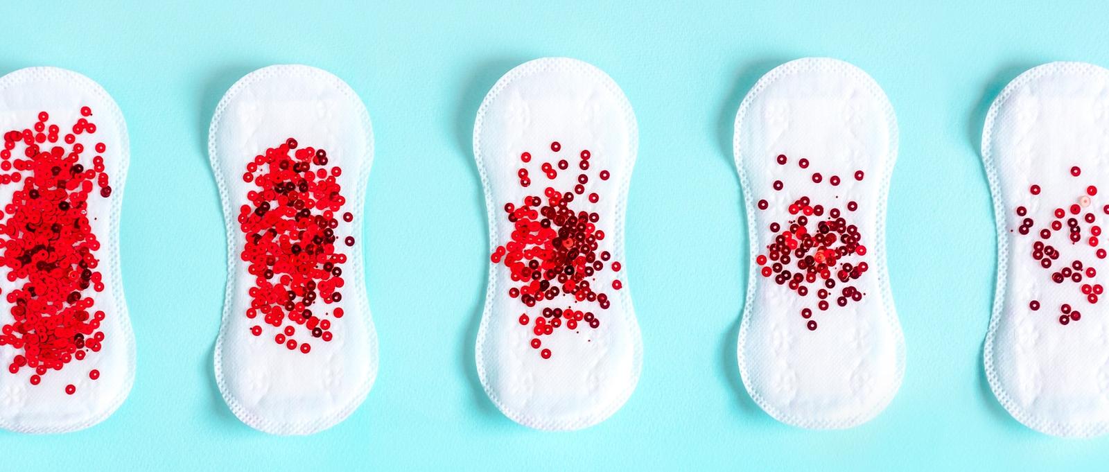 Menstrual pads with red glitter on blue colored background.