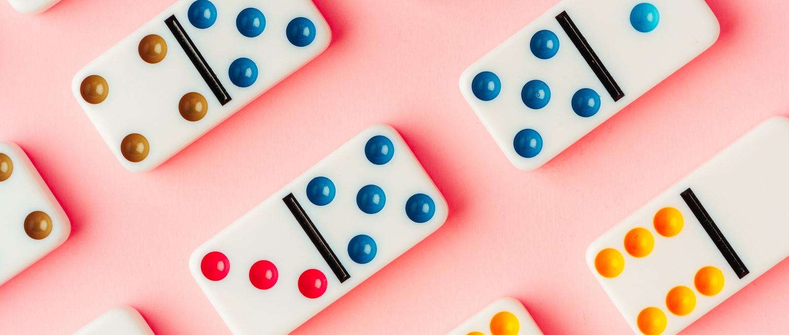 A pattern of domino pieces on pink background top view