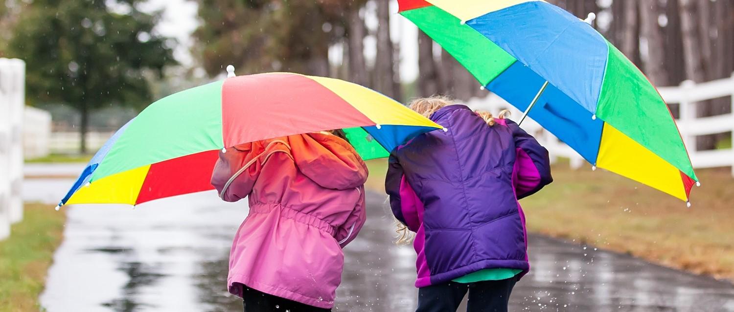 Children playing in puddles holding umbrella
