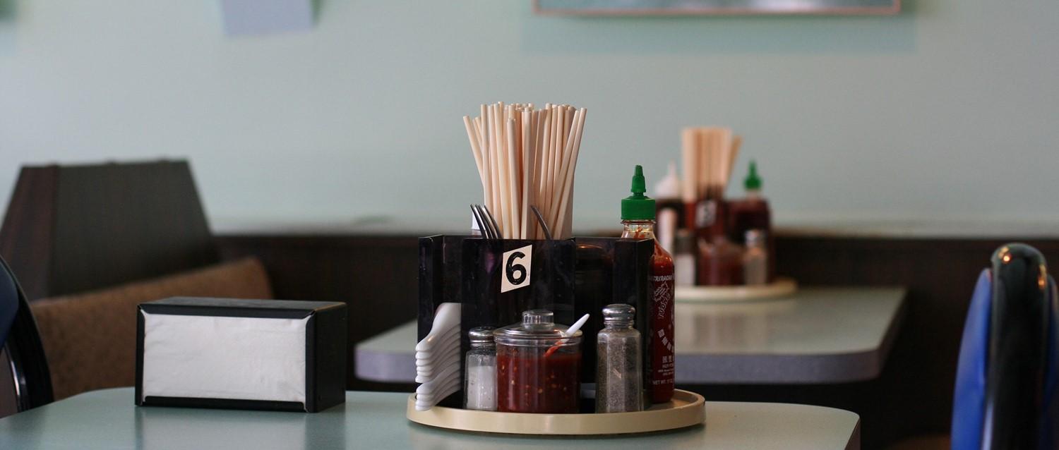Restaurant table setting with chopsticks, condiments and napkins in a holder marked with number 6.