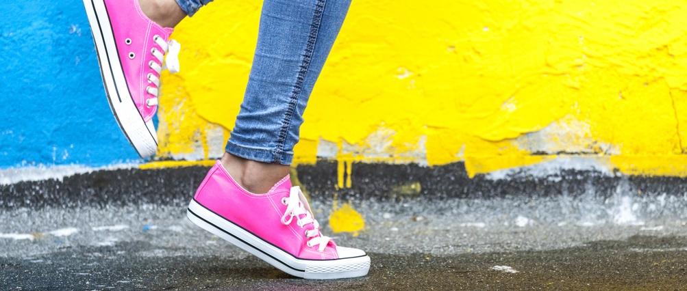 Woman in pink sneakers against yellow and blue wall